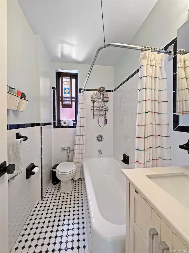 Bathroom featuring shower / bath combo, tile walls, vanity, and light tile patterned floors
