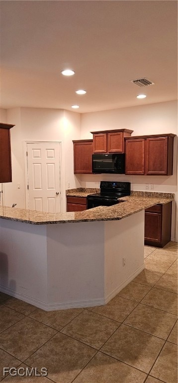 Kitchen featuring black electric range, light ston