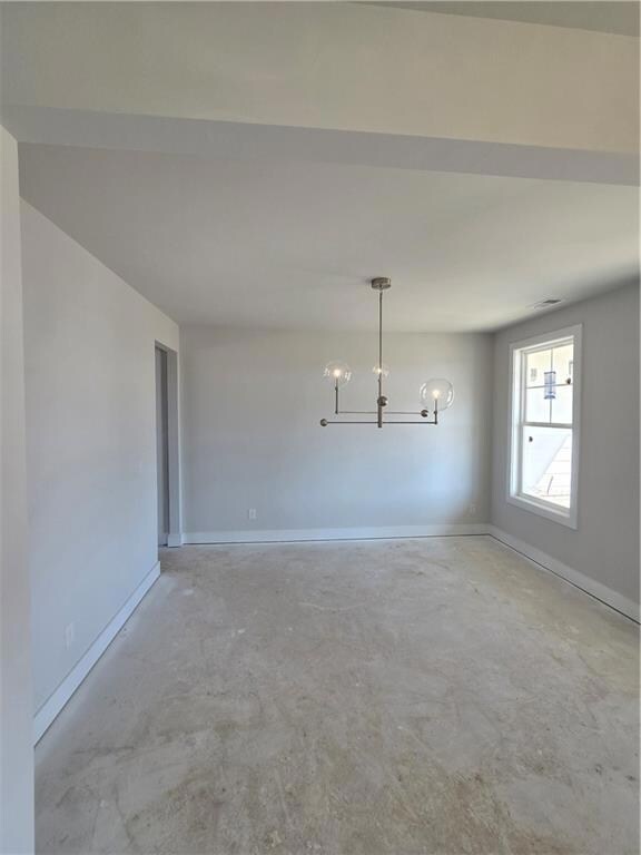 Unfurnished dining area featuring unfinished concrete floors and a chandelier