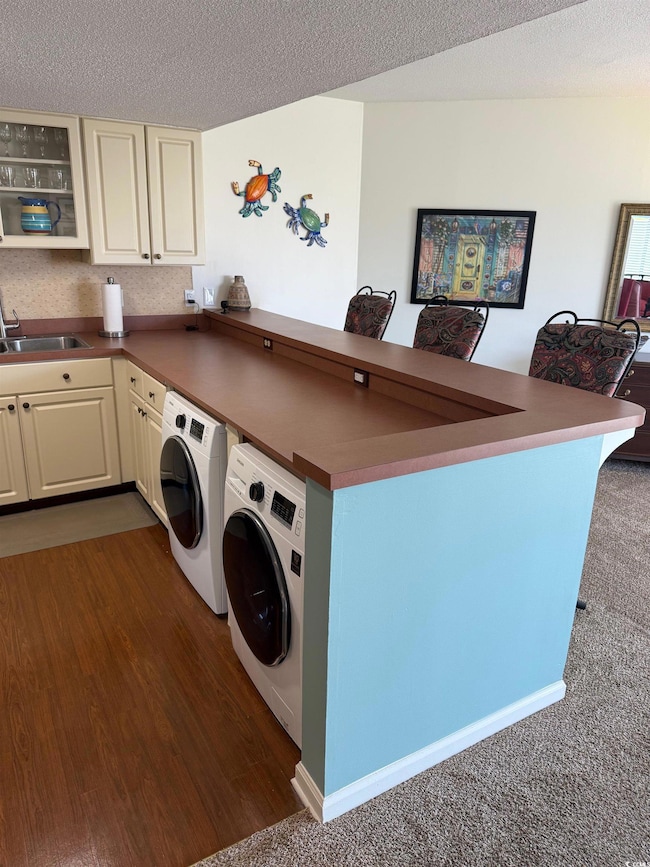 Laundry room with a textured ceiling, a sink, wash