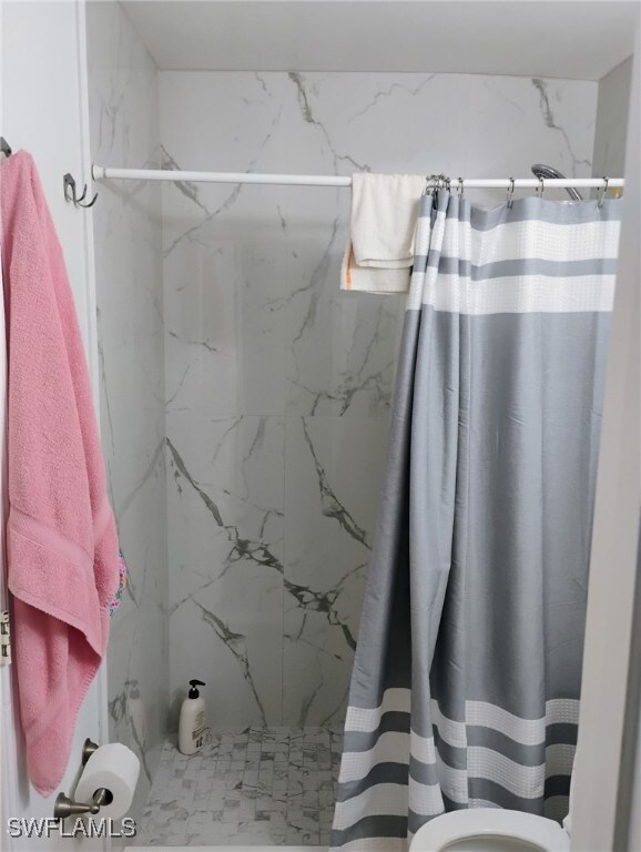 Full bath featuring a marble finish shower