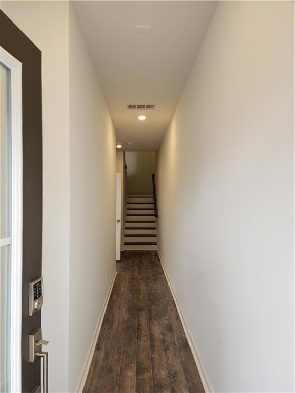 Hallway with dark wood-style floors, baseboards, v