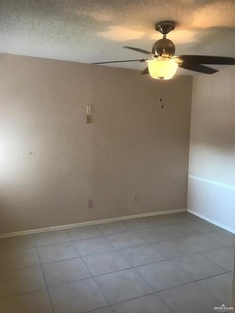 Empty room with a textured ceiling, tile floors, and ceiling fan
