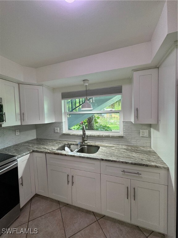 Kitchen featuring range, sink, white cabinetry, de