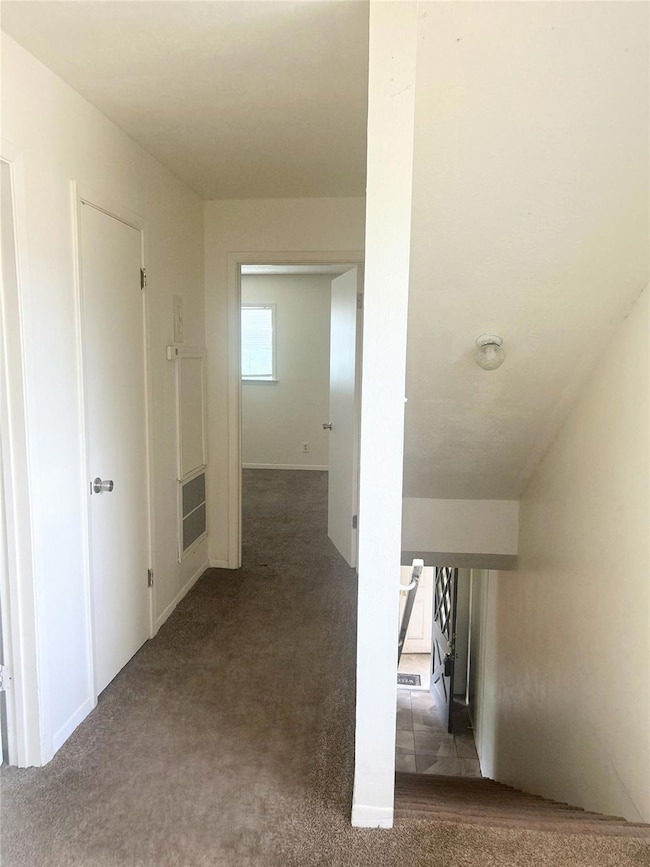 Hallway with carpet and baseboards