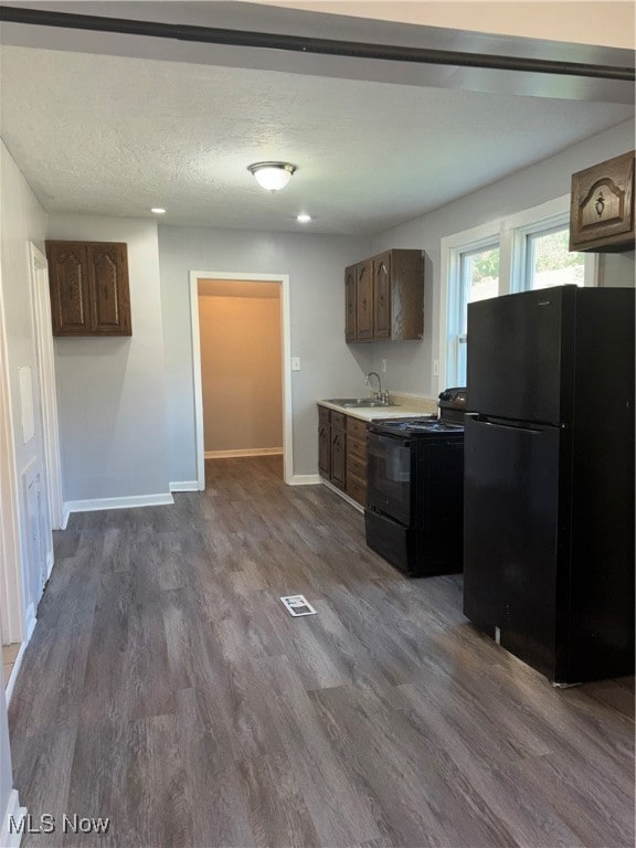 Kitchen featuring fridge, range, dark wood-style flooring, and light countertops