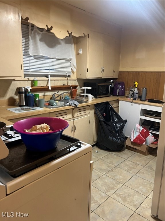 Kitchen with washer / clothes dryer, light countertops, light tile patterned floors, black microwave, and wooden walls