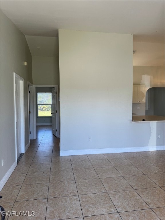 Unfurnished room with light tile patterned flooring and high vaulted ceiling
