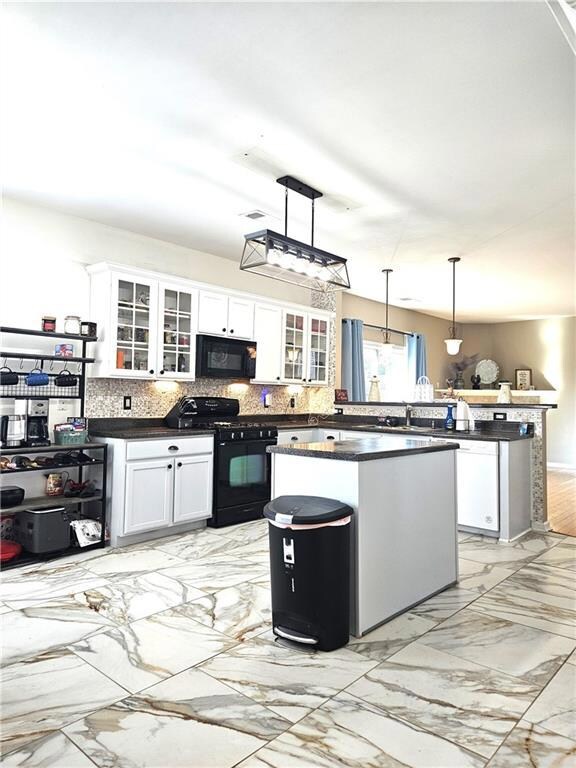 Kitchen featuring light marble finish floors, white cabinetry, hanging light fixtures, and tasteful backsplash