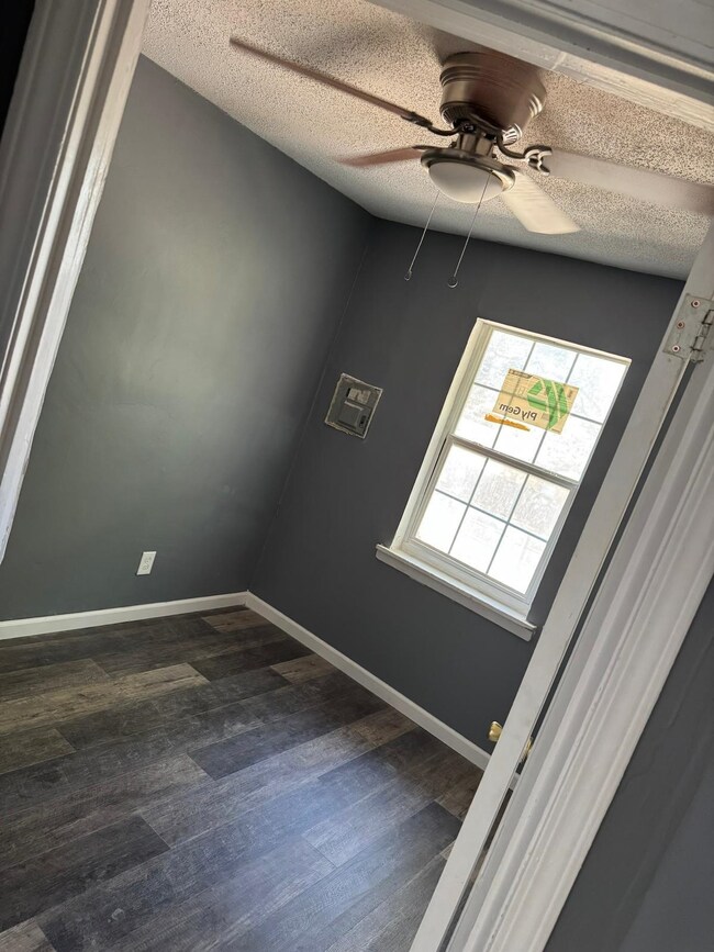 Spare room with dark wood finished floors, ceiling fan, a textured ceiling, and baseboards