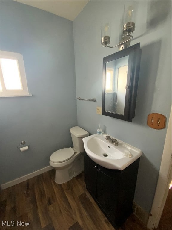 Bathroom with toilet, vanity, plenty of natural light, and wood finished floors