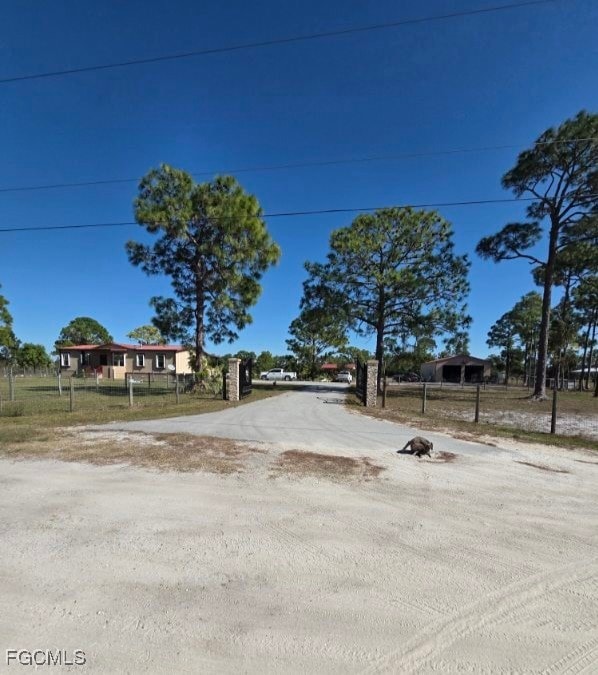 View of dirt / gravel driveway with a gated entry