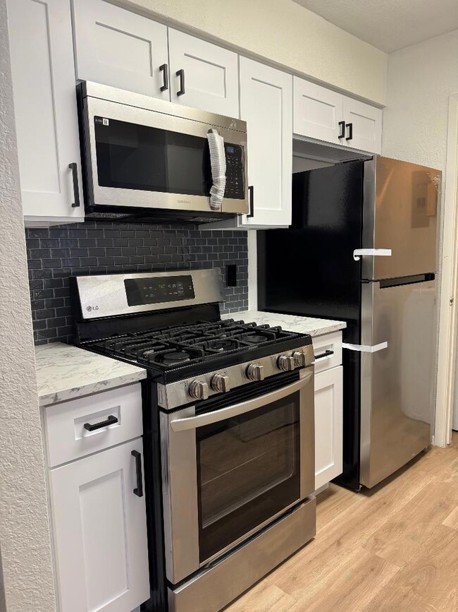 Kitchen featuring Stainless Steel Appliances,white cabinetry, light wood style flooring,