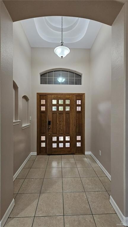 Tiled entrance foyer with a tray ceiling and a towering ceiling
