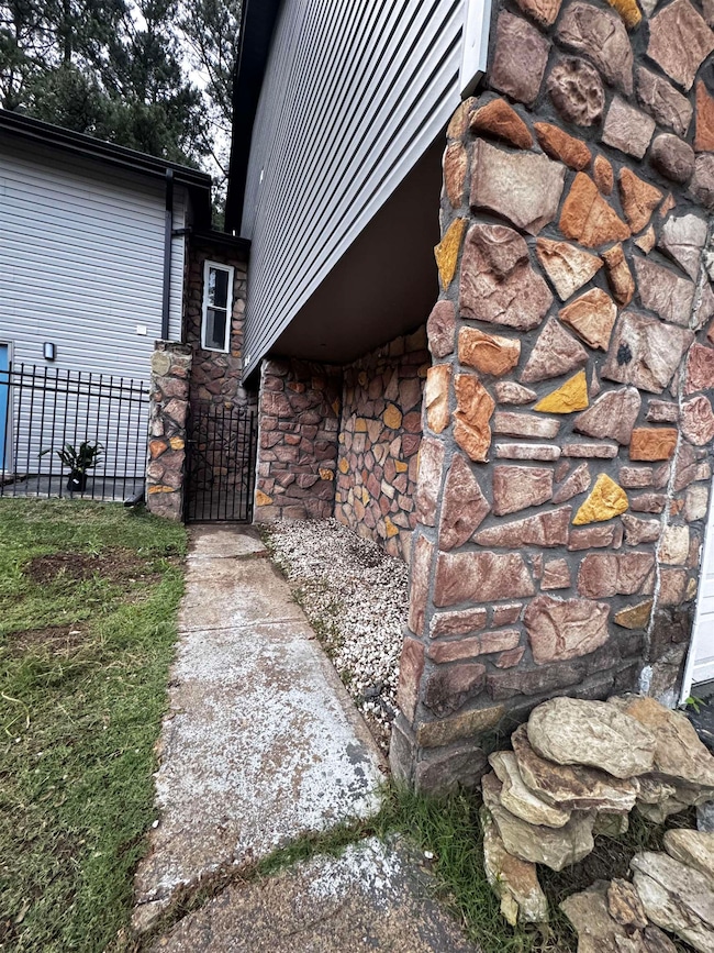 View of side of property with stone siding, fence,