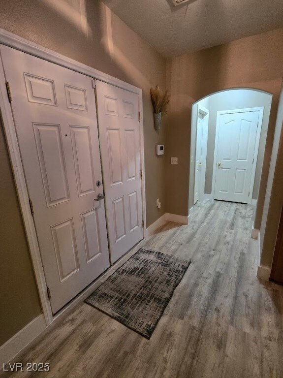 Foyer entrance with light wood-style floors, arche