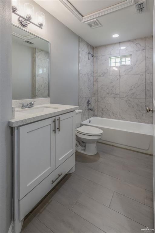 Full bathroom featuring vanity, tiled shower / bath combo, toilet, and tile patterned flooring