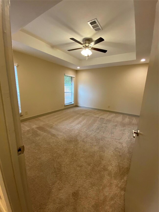 Carpeted spare room with ceiling fan and a raised 