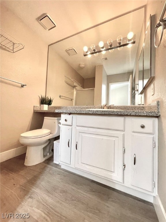 Bathroom featuring toilet, vanity, wood finished f