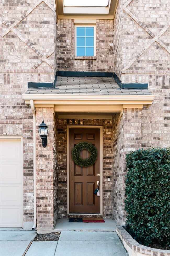 Property entrance featuring a garage and brick sid