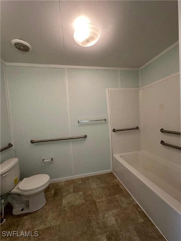 Bathroom featuring shower / tub combination, a textured ceiling, and toilet