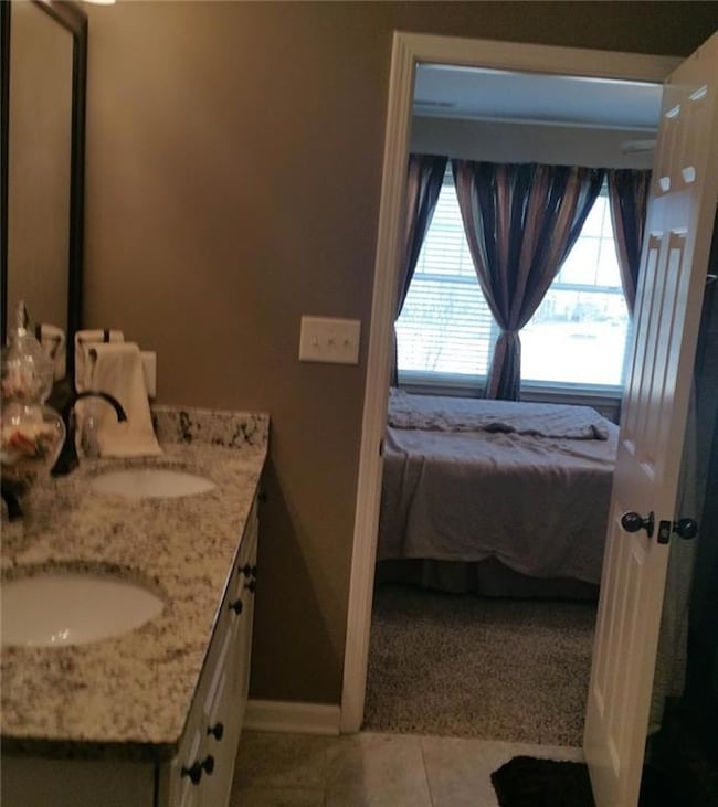 Bathroom featuring ensuite bathroom, double vanity, and light tile patterned flooring
