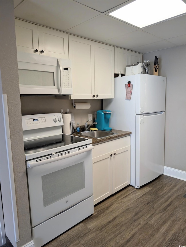Kitchen with dark wood-type flooring, white applia