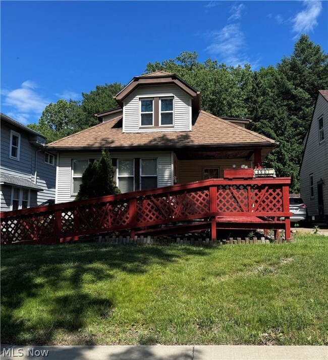 View of front facade with a front lawn and a wooden deck