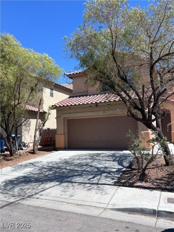 Mediterranean / spanish house with concrete driveway, a garage, stucco siding, and a tile roof