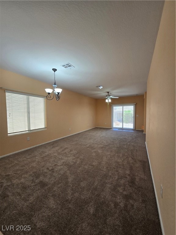Spare room with dark colored carpet, a chandelier,