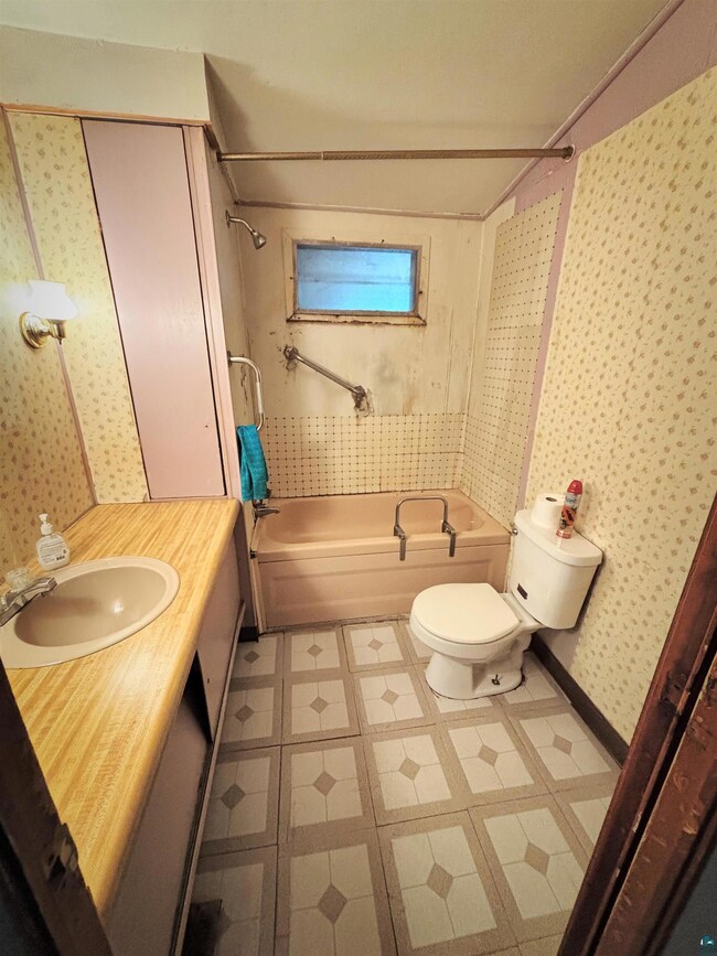Full bath with toilet, tile patterned floors, wall