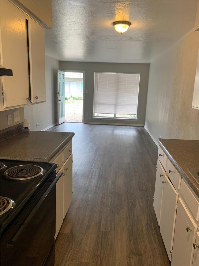 Kitchen with dark wood-style floors, a textured ce