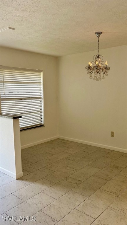 Empty room with a chandelier, a textured ceiling,