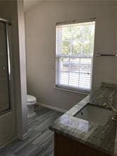 Full bathroom featuring vanity, toilet, baseboards, shower / bath combination with glass door, and wood finished floors