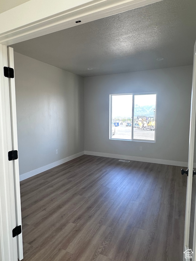 Unfurnished room with dark wood finished floors and a textured ceiling