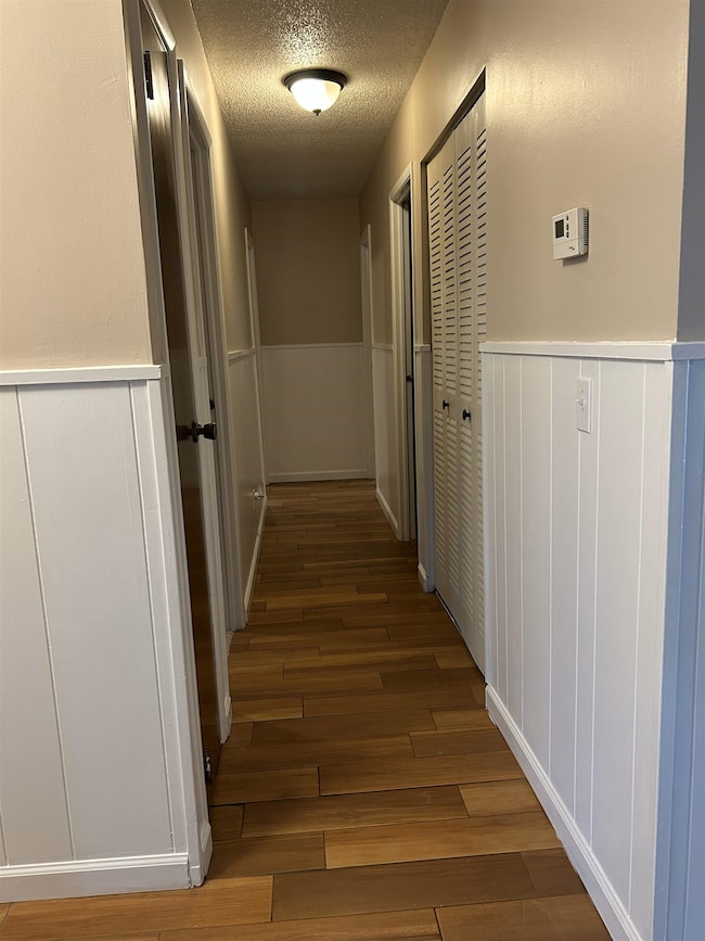 Hallway featuring wood finished floors, a textured