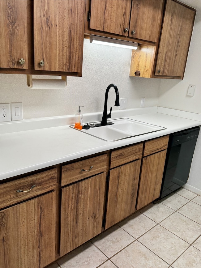 Efficient galley-style kitchen with ample wood cabinetry, bright countertops, and upgraded black faucet. Under-cabinet lighting enhances functionality for everyday cooking and cleanup.