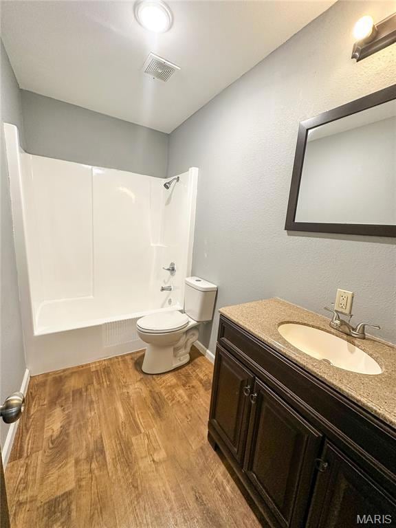 Full bathroom with bathing tub / shower combination, vanity, light wood finished floors, and a textured wall