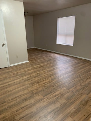 Empty room featuring dark wood finished floors and baseboards
