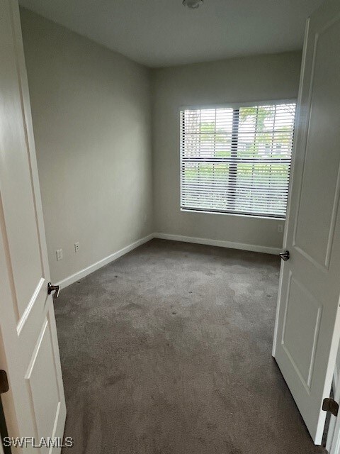 Unfurnished room featuring carpet floors and baseb