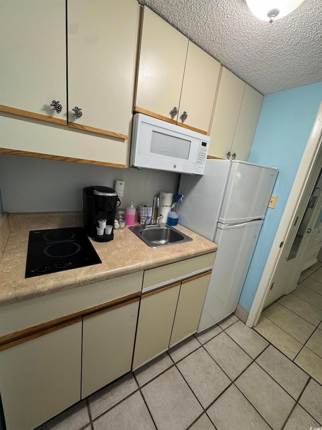 Kitchen featuring white appliances, a sink, light 