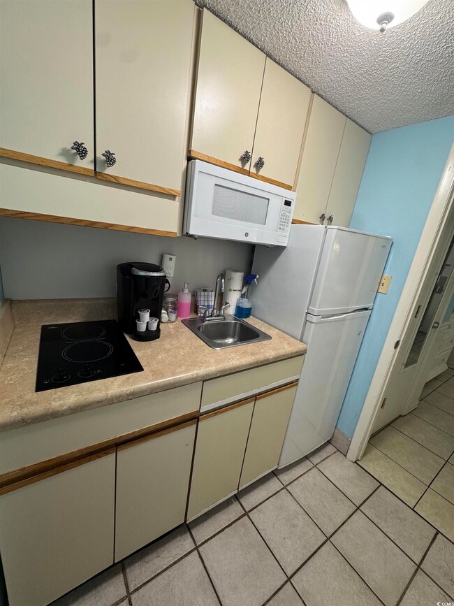 Kitchen featuring white appliances, a sink, light 