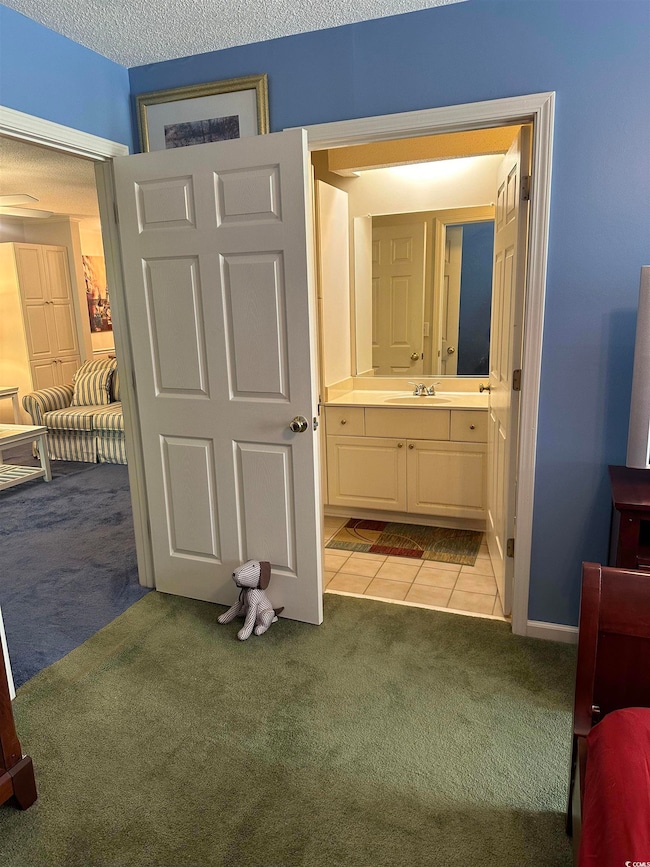 Bathroom featuring carpet floors, vanity, tile patterned floors, and baseboards