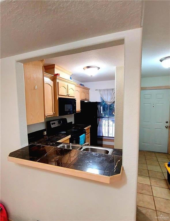Kitchen with stainless steel electric range oven, a textured ceiling, tile patterned floors, black microwave, and light brown cabinets