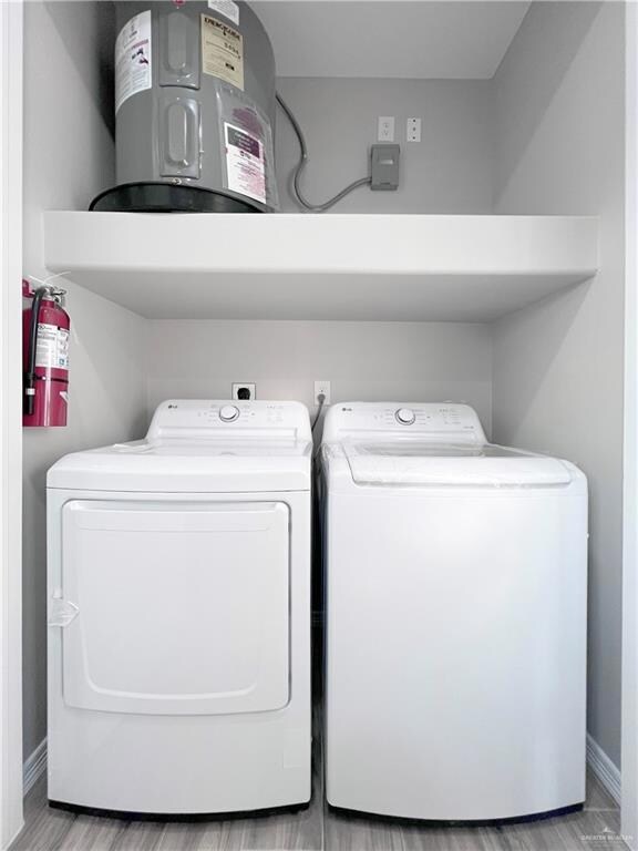 Laundry area with washer and clothes dryer, baseboards, and electric water heater