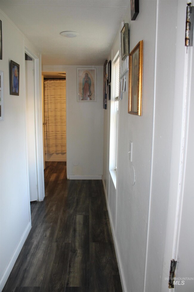 Hallway featuring dark wood finished floors and baseboards