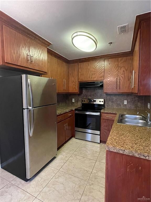 Kitchen with stainless steel electric stove, granite countertops, and fridge