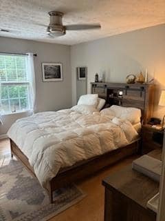 Bedroom featuring wood finished floors, a textured ceiling, and a ceiling fan