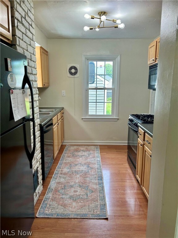 Kitchen featuring light hardwood / wood-style flooring, black appliances, a chandelier, sink, and light brown cabinets