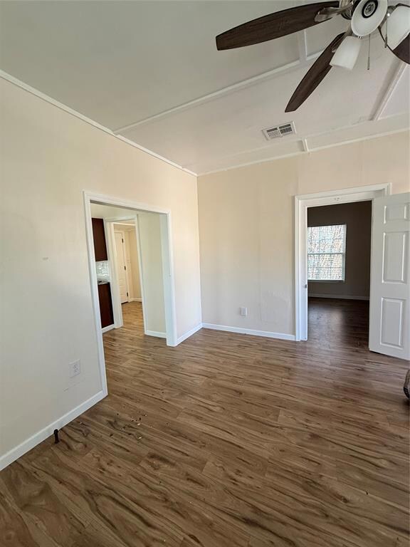 Unfurnished room featuring ceiling fan and dark ha